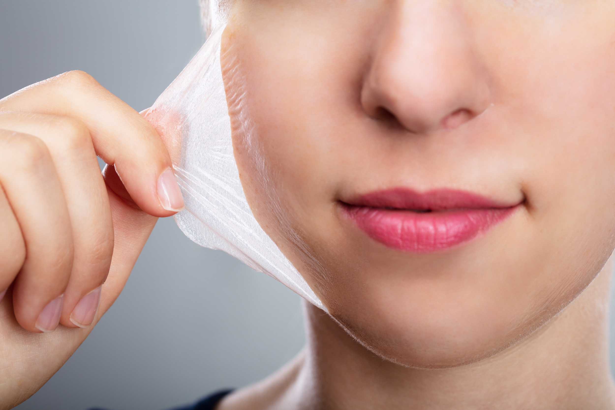 Portrait Of A Beautiful Young Woman Removing Peeling Mask From Her Face